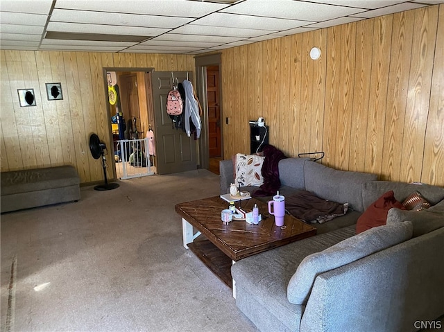 carpeted living room featuring a paneled ceiling and wood walls