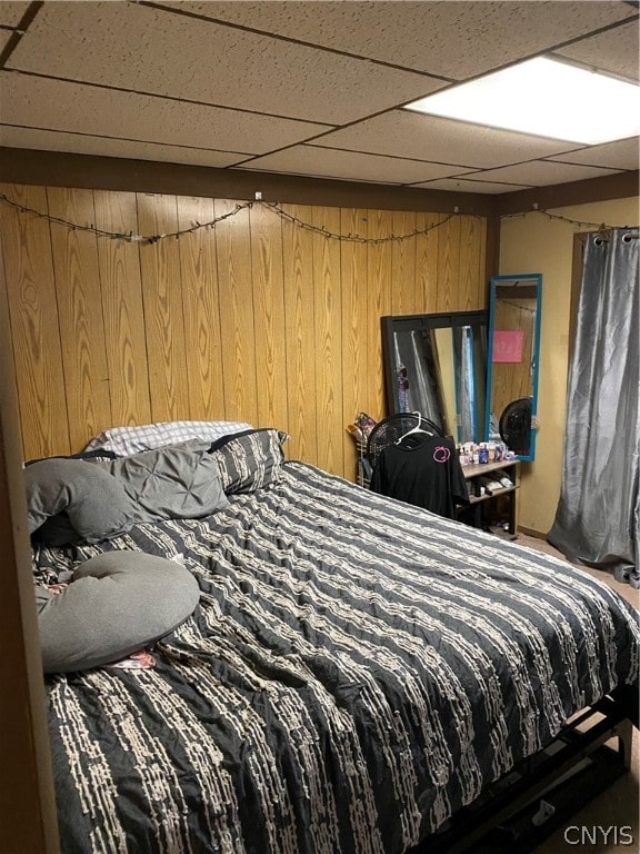 bedroom with wooden walls and a paneled ceiling