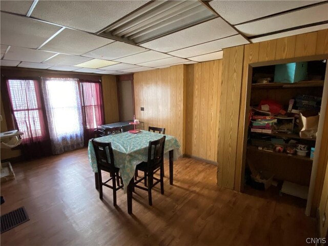 dining area with wood walls, hardwood / wood-style floors, and a paneled ceiling