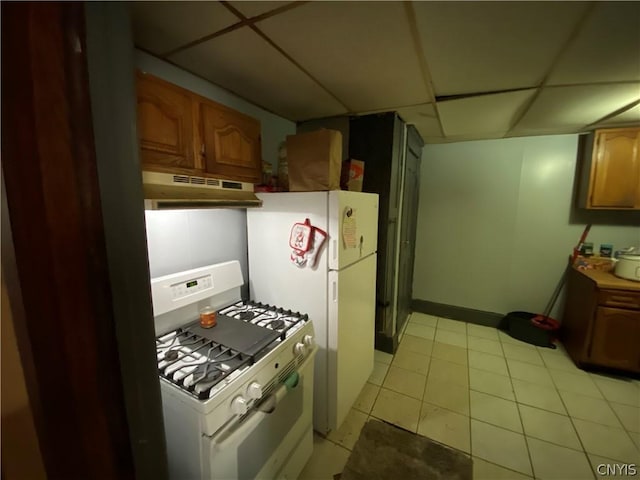 kitchen with brown cabinets, a paneled ceiling, light tile patterned flooring, white appliances, and under cabinet range hood