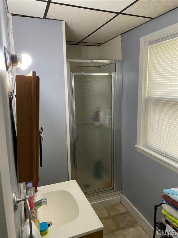 bathroom featuring walk in shower, a drop ceiling, vanity, and tile patterned floors