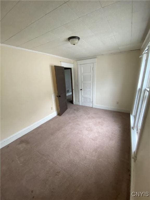 spare room with ornamental molding, carpet flooring, and baseboards