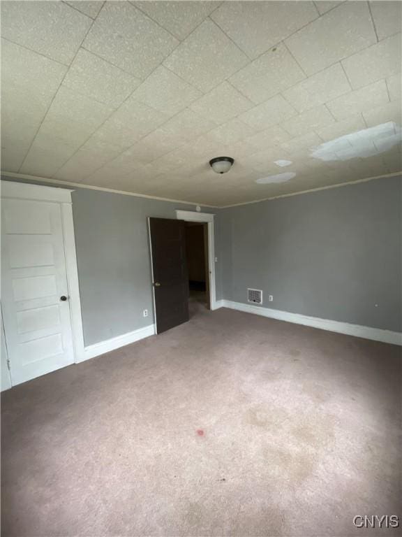 empty room with carpet flooring, visible vents, and baseboards