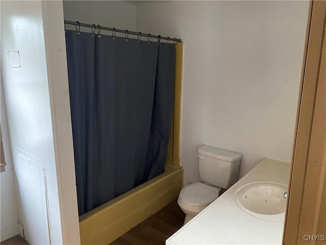 bathroom featuring shower / bath combination with curtain, a sink, toilet, and wood finished floors