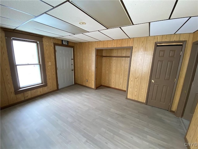 unfurnished bedroom with wood walls, light wood-type flooring, and a closet