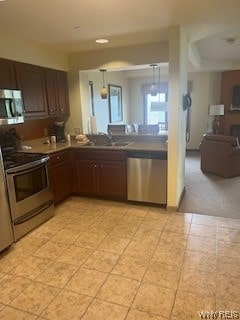 kitchen featuring sink, stainless steel appliances, pendant lighting, dark brown cabinets, and light colored carpet