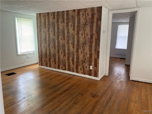 empty room featuring wood-type flooring and a paneled ceiling