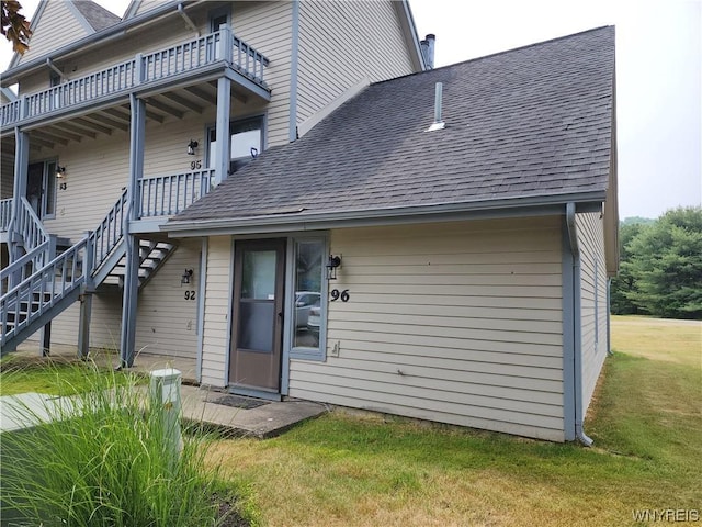 rear view of property featuring a lawn and a balcony