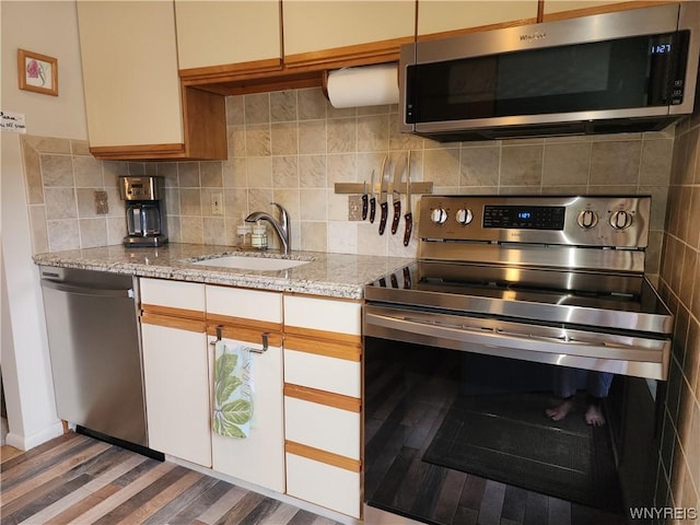 kitchen featuring backsplash, sink, light stone counters, white cabinetry, and stainless steel appliances