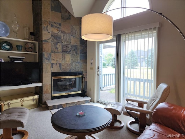 living room with a tiled fireplace, a wealth of natural light, and vaulted ceiling