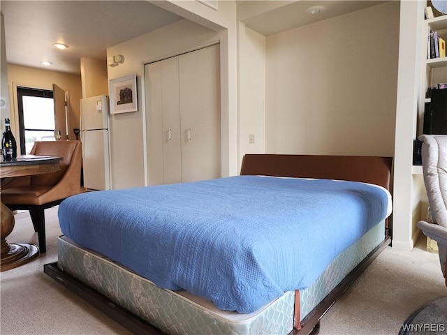 carpeted bedroom featuring a closet and white refrigerator