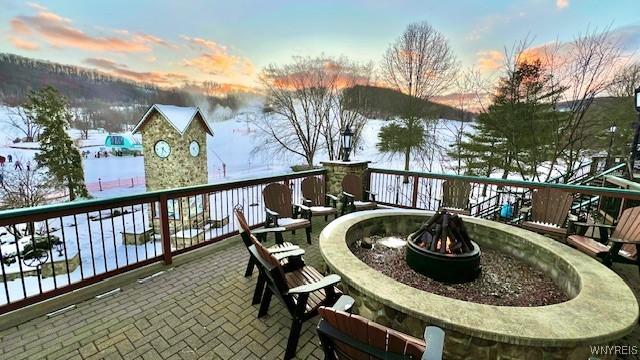 snow covered back of property with an outdoor fire pit