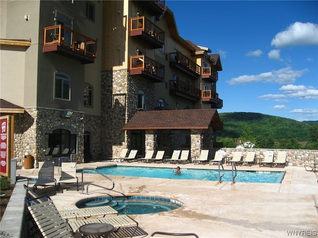 view of swimming pool with a community hot tub, a mountain view, and a patio area