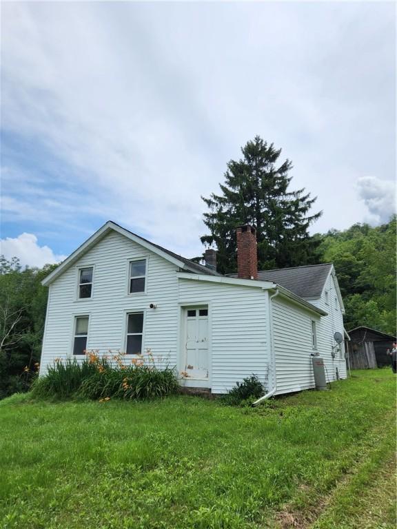 rear view of property featuring a yard and a chimney