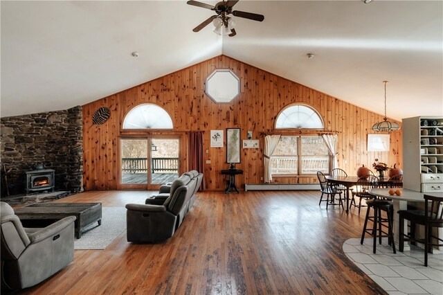 living room with a wood stove, ceiling fan, plenty of natural light, and hardwood / wood-style flooring