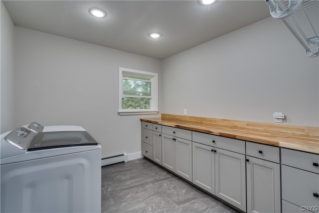 washroom with washer and clothes dryer, cabinets, a baseboard radiator, and light tile floors