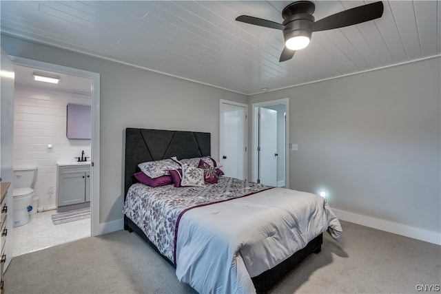 carpeted bedroom with ensuite bathroom, ceiling fan, and sink