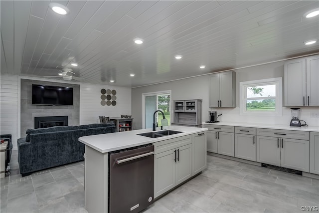 kitchen with stainless steel dishwasher, a fireplace, ceiling fan, sink, and light tile flooring