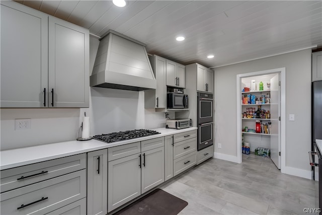 kitchen with gray cabinetry, stainless steel appliances, and custom exhaust hood