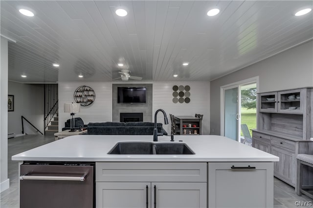 kitchen featuring a fireplace, sink, an island with sink, stainless steel dishwasher, and wooden ceiling