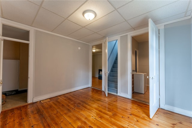 unfurnished bedroom with light hardwood / wood-style floors, a drop ceiling, and washer / dryer