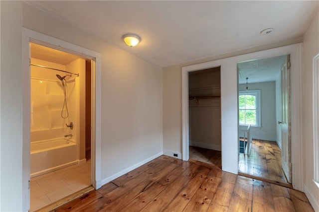 unfurnished bedroom featuring tile flooring, a closet, connected bathroom, and a walk in closet