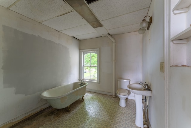 bathroom featuring a paneled ceiling, toilet, a washtub, and tile floors