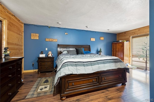 bedroom with wood walls, dark hardwood / wood-style floors, and a textured ceiling