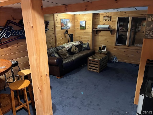 carpeted living room with beamed ceiling and wood walls