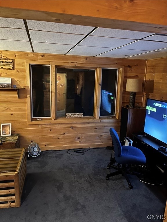 carpeted office with wooden walls and a paneled ceiling