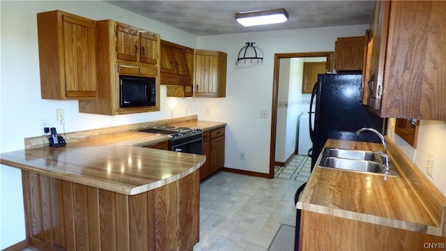 kitchen with premium range hood, light tile floors, sink, kitchen peninsula, and black appliances