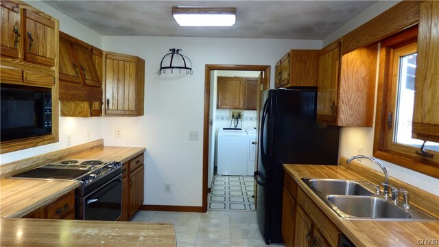 kitchen featuring a healthy amount of sunlight, sink, light tile floors, and black appliances