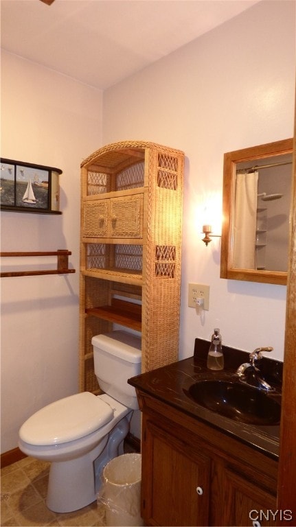 bathroom with toilet, large vanity, and tile flooring