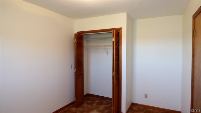 unfurnished bedroom featuring a closet and dark carpet