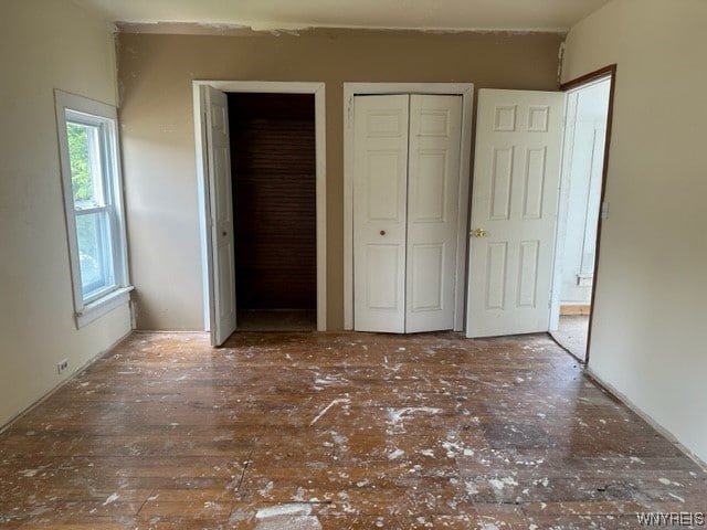 unfurnished bedroom with dark hardwood / wood-style flooring and multiple closets