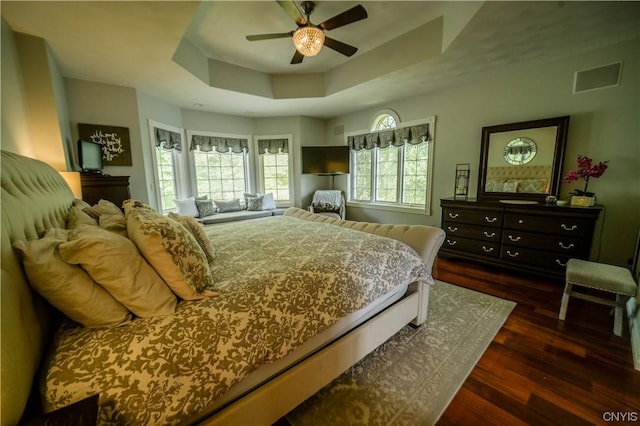 bedroom featuring ceiling fan, dark hardwood / wood-style floors, and a tray ceiling