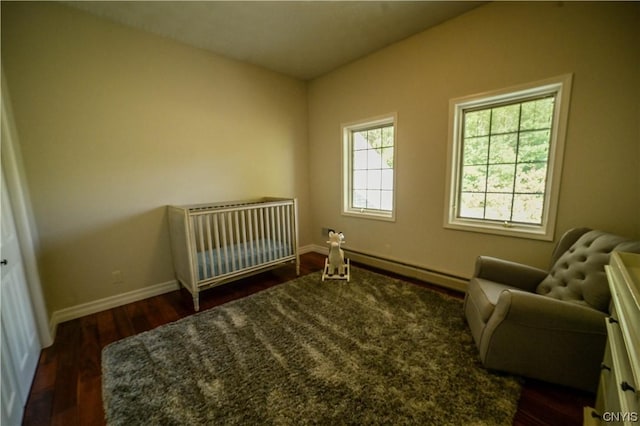 bedroom with a baseboard radiator, a crib, and dark hardwood / wood-style flooring