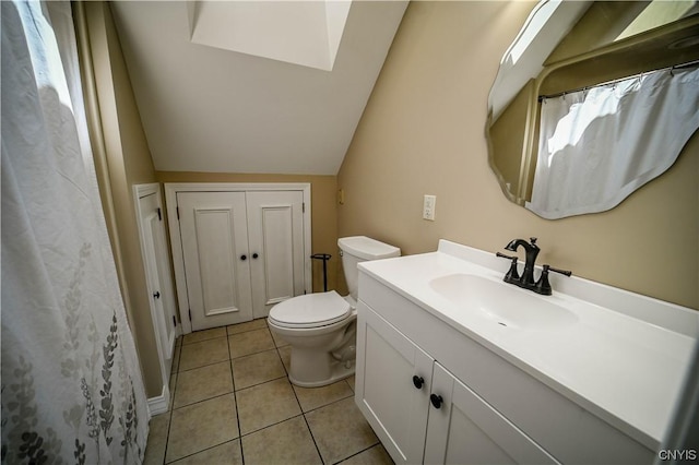 bathroom featuring toilet, tile patterned flooring, lofted ceiling with skylight, and vanity