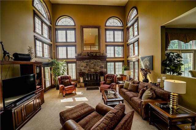 sitting room featuring a towering ceiling, light carpet, and a stone fireplace