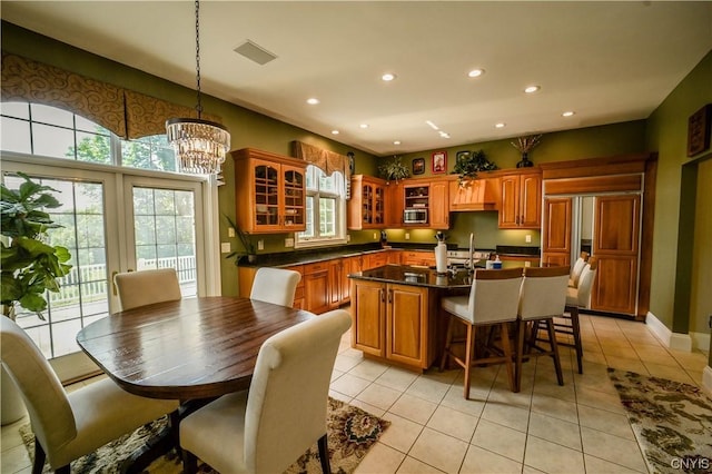 kitchen featuring hanging light fixtures, a center island with sink, a notable chandelier, a breakfast bar area, and light tile patterned flooring