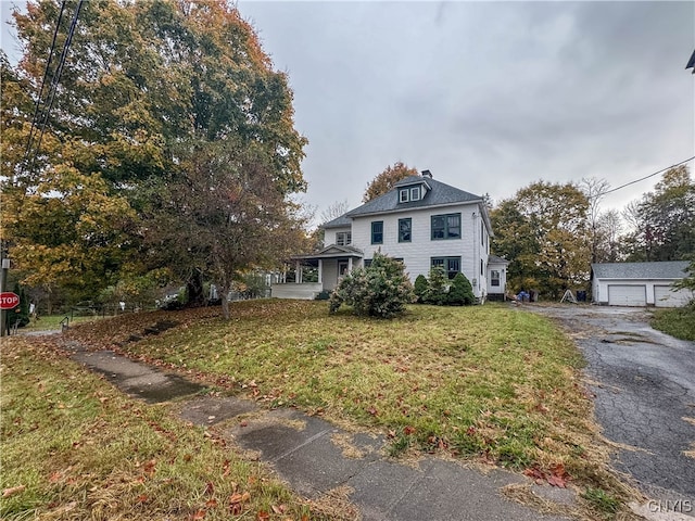 view of front of home with a garage, a front lawn, and an outbuilding