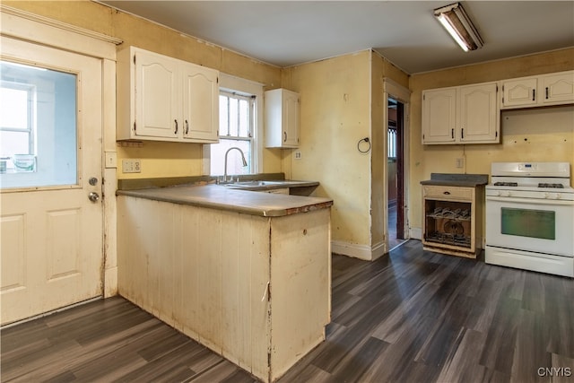 kitchen featuring dark hardwood / wood-style floors, white gas range oven, white cabinets, and sink