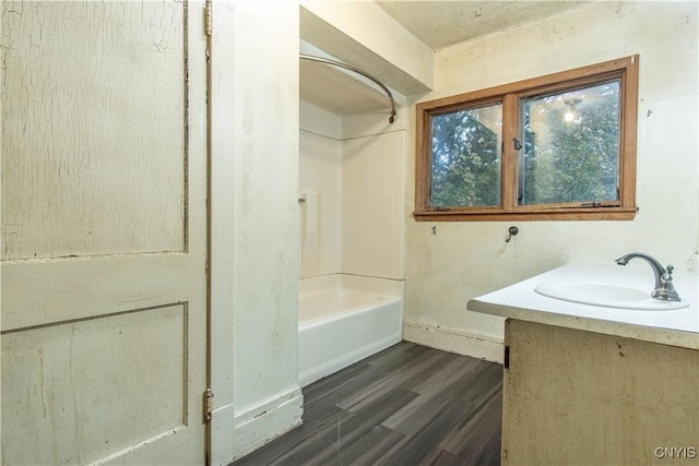 bathroom featuring baseboards, wood finished floors, shower / washtub combination, and vanity