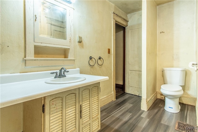 bathroom with vanity, toilet, and hardwood / wood-style flooring