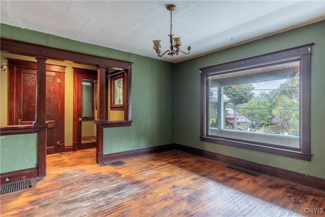 empty room featuring hardwood / wood-style flooring and a notable chandelier