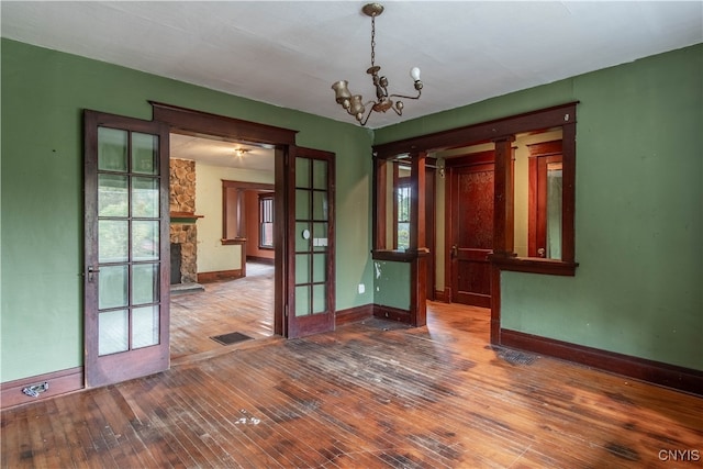 empty room with wood-type flooring, french doors, and a chandelier