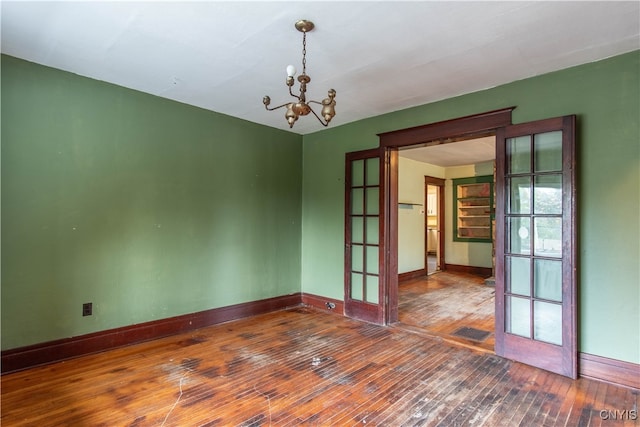 empty room featuring a chandelier, dark hardwood / wood-style floors, and french doors