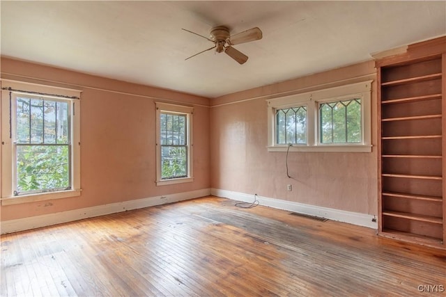 unfurnished room featuring baseboards, visible vents, ceiling fan, and wood-type flooring