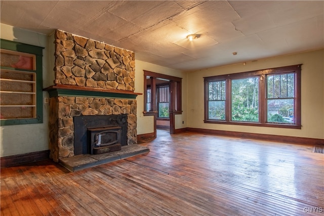 unfurnished living room featuring hardwood / wood-style flooring and a wood stove