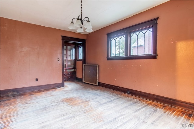 unfurnished room with hardwood / wood-style floors and a notable chandelier